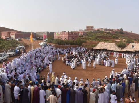 Large outdoor gathering in a Moroccan village, showcasing cultural and traditional attire. Large outdoor gathering in a Moroccan village, showcasing cultural and traditional attire.