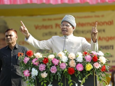 Man delivering a powerful public speech outdoors with a floral adorned podium.