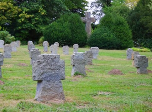 Peaceful cemetery scene with stone crosses and greenery during daytime.