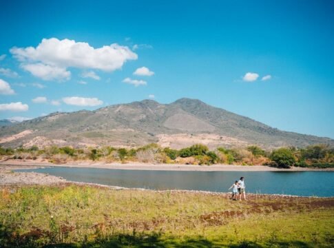 Scenic view of hikers by a lake with stunning mountain backdrop in El Salvador, perfect for outdoor adventures.