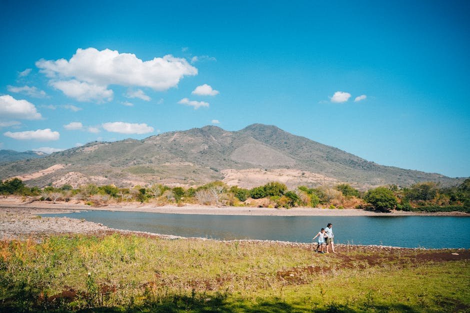 Scenic view of hikers by a lake with stunning mountain backdrop in El Salvador, perfect for outdoor adventures.