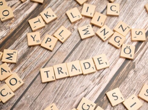 Scrabble letter tiles spelling 'trade' on a wooden surface, illustrating business concepts.