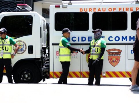 Security officers in safety vests beside an emergency response vehicle. Security officers in safety vests beside an emergency response vehicle.