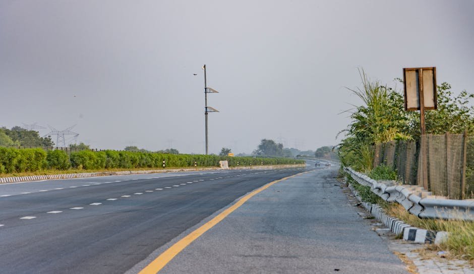 Uttar Pradesh’s Lucknow-Kanpur Expressway Nears Opening Amidst Toll Concerns Serene landscape of an empty expressway in Deeg, India with lush greenery.