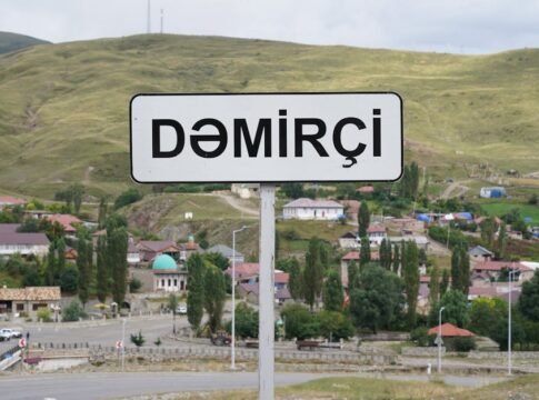 Signpost of Demirci village against a hilly landscape, showcasing small houses and lush greenery. Signpost of Demirci village against a hilly landscape, showcasing small houses and lush greenery.