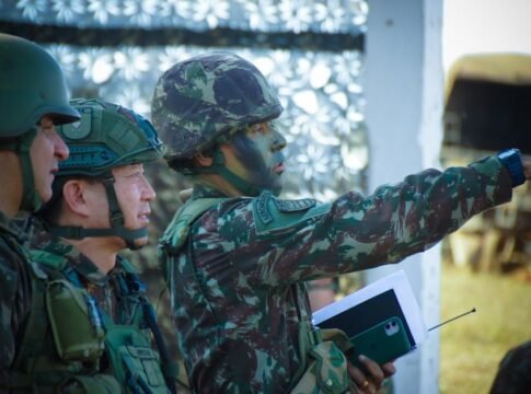 Soldiers in camouflage and helmets strategizing outdoors, focusing on a mission directive.