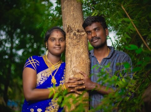 South Asian couple in traditional attire embracing a tree, symbolizing love and nature.