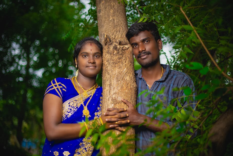 South Asian couple in traditional attire embracing a tree, symbolizing love and nature.