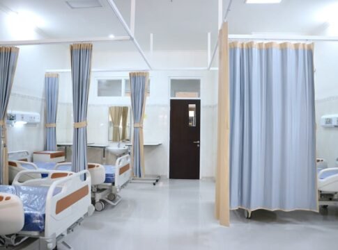 Spacious hospital ward in Surabaya, Indonesia with multiple medical beds and privacy curtains.