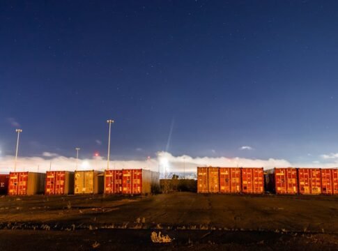 Stacked shipping containers on industrial site with star-filled night sky backdrop. Stacked shipping containers on industrial site with star-filled night sky backdrop.