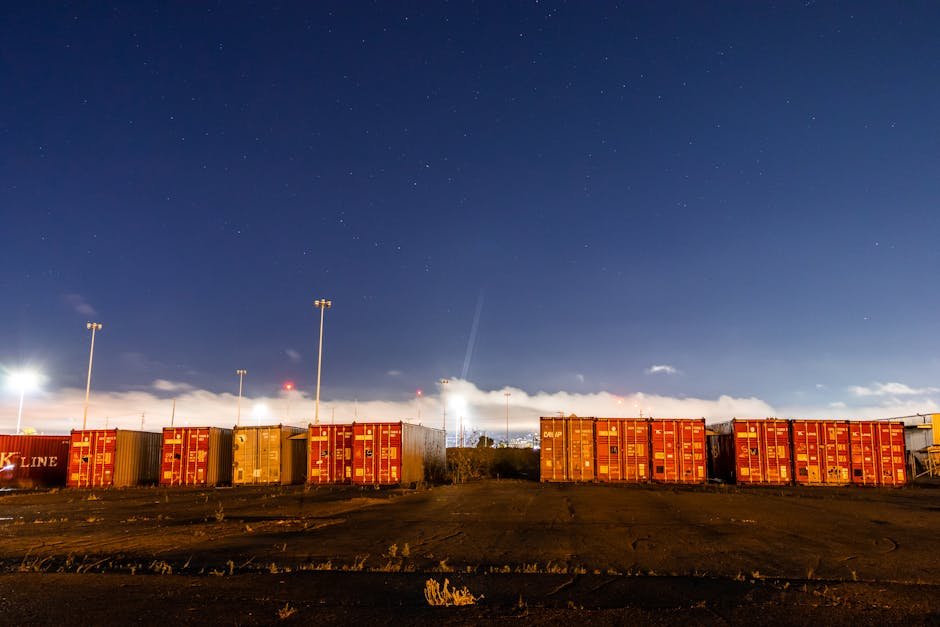 Stacked shipping containers on industrial site with star-filled night sky backdrop. Stacked shipping containers on industrial site with star-filled night sky backdrop.