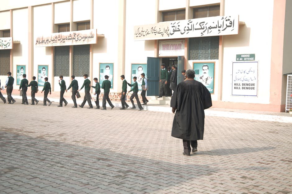 Jammu and Kashmir School Safety Regulations Undergo Consultative Process in Srinagar Students in uniform lined up at a school entrance with a teacher overseeing.