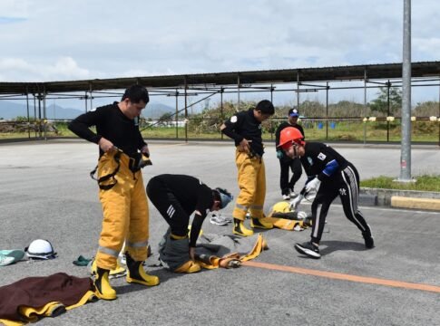 Team of firefighters preparing equipment during an outdoor training exercise on a sunny day.