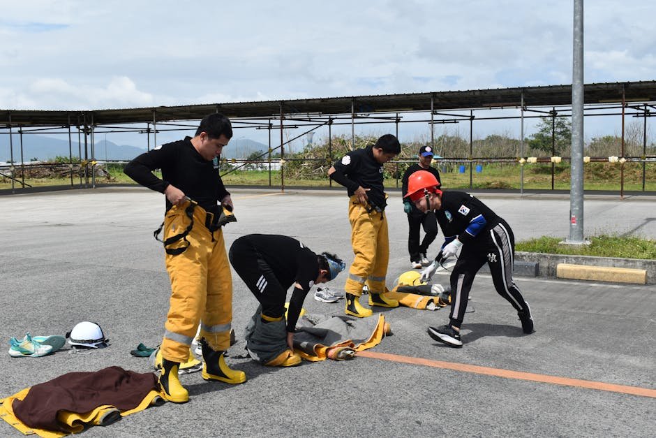 Team of firefighters preparing equipment during an outdoor training exercise on a sunny day.