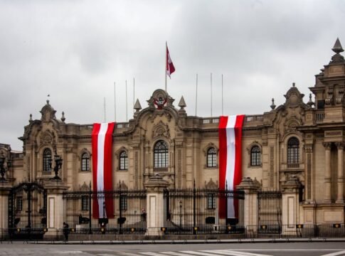The Presidential Palace in Lima, Peru, with vibrant red and white flags displayed on the facade.