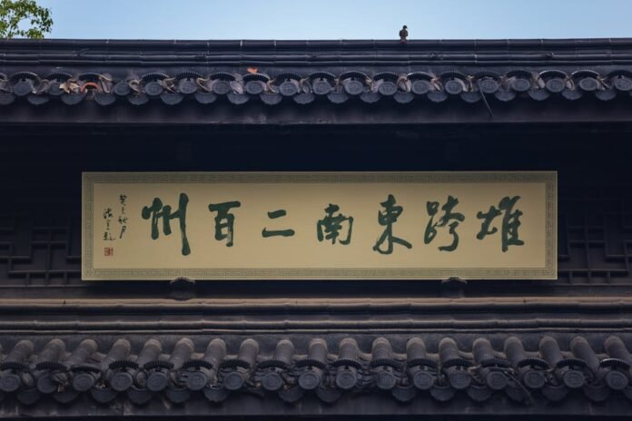 Traditional building exterior with Chinese characters on sign and decorative roof, featuring a small bird.