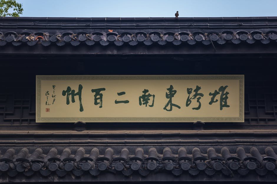 Traditional building exterior with Chinese characters on sign and decorative roof, featuring a small bird. Traditional building exterior with Chinese characters on sign and decorative roof, featuring a small bird.