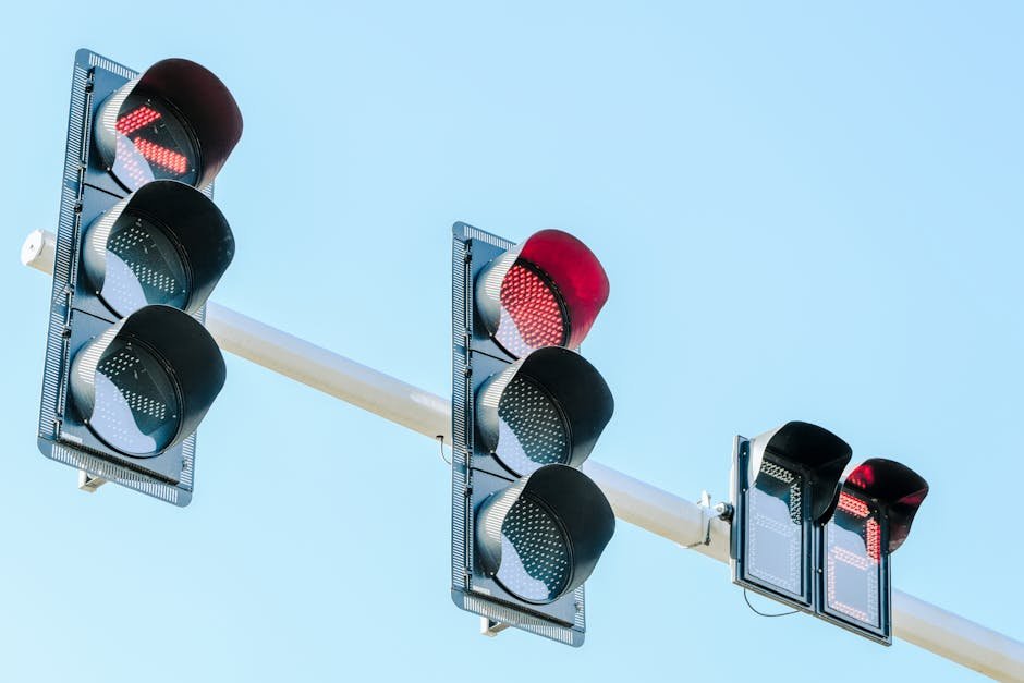 Traffic lights showing red against a clear blue sky on a sunny day.