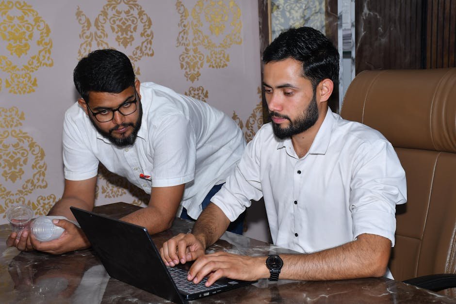 Rajasthan Batter Mukul Choudhary Smashes Sixes to Clinch IPL Thriller for Lucknow Two men working together at a desk, focused on a laptop, showcasing teamwork and collaboration.