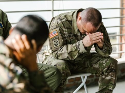 Two soldiers in military uniforms expressing emotions indoors, depicting stress and companionship. Two soldiers in military uniforms expressing emotions indoors, depicting stress and companionship.