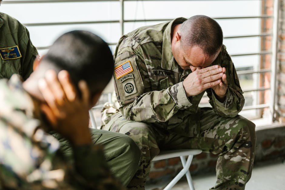 Two soldiers in military uniforms expressing emotions indoors, depicting stress and companionship.