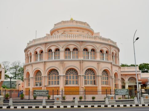 A beautiful pink circular building with arched windows and ornate architecture in a city setting. A beautiful pink circular building with arched windows and ornate architecture in a city setting.