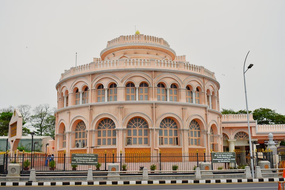 Tamil Nadu Establishes Talent Research Wing to Nurture Meritorious Sportspersons A beautiful pink circular building with arched windows and ornate architecture in a city setting.
