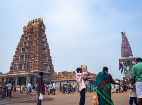 A busy day at a historic temple in India with numerous visitors and traditional rituals.