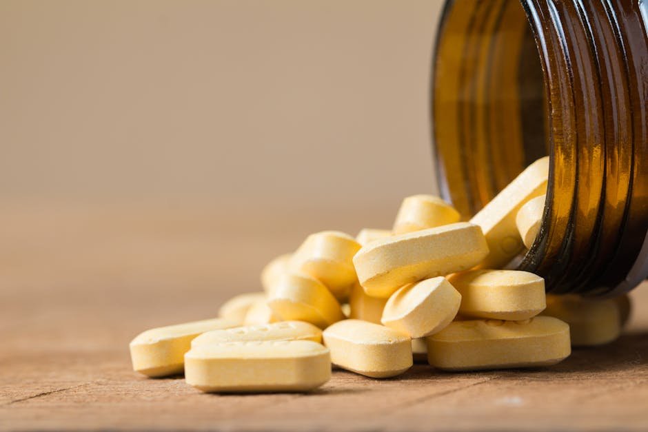 India Study Links Vitamin B12, Folate Deficiencies to Fatigue and Reduced Motivation A close-up image of vitamin tablets spilling out of a transparent brown bottle on a wooden surface.