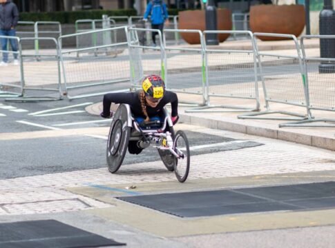 A dedicated athlete competes in a marathon using a racing wheelchair on city streets.