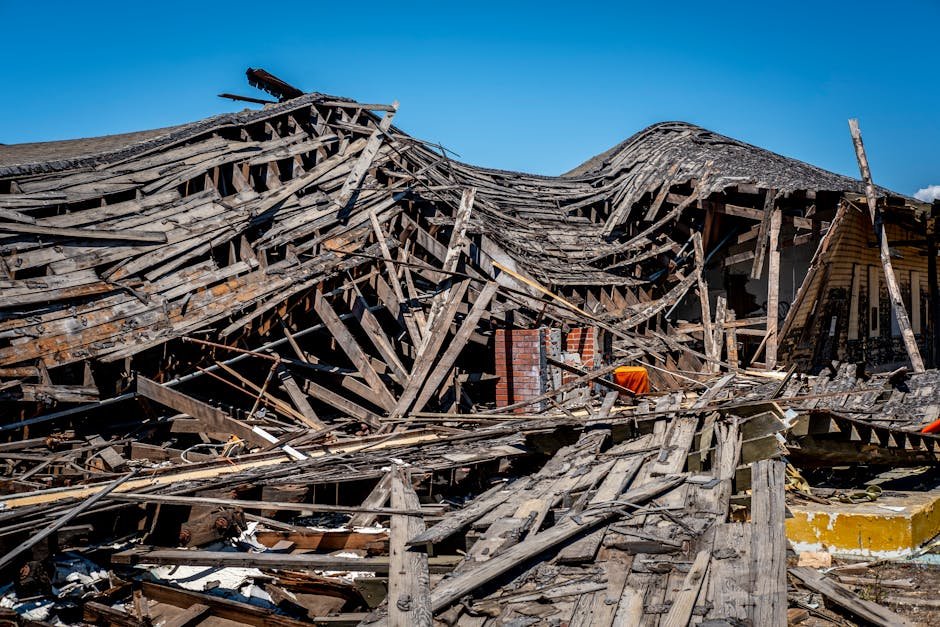Four Family Members Die in Roof Collapse Amid Heavy Rains in Vijayapura, Karnataka A dramatic view of a destroyed wooden building after a catastrophe, showing debris and structural failure.