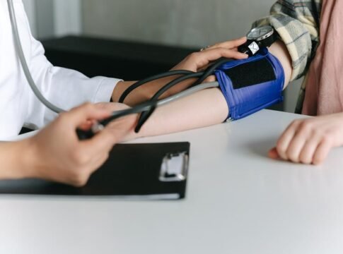 A healthcare worker uses a sphygmomanometer to check a patient's blood pressure in a medical office.