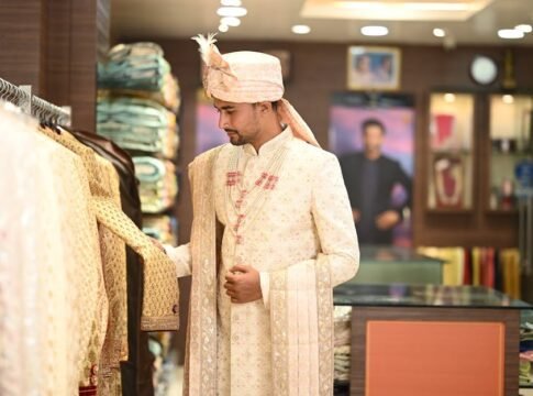 A man in traditional attire shopping in an Indian clothing store, showcasing cultural fashion.