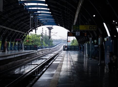 A quiet afternoon at a New Delhi metro station with wet tracks post rain, reflecting urban life.
