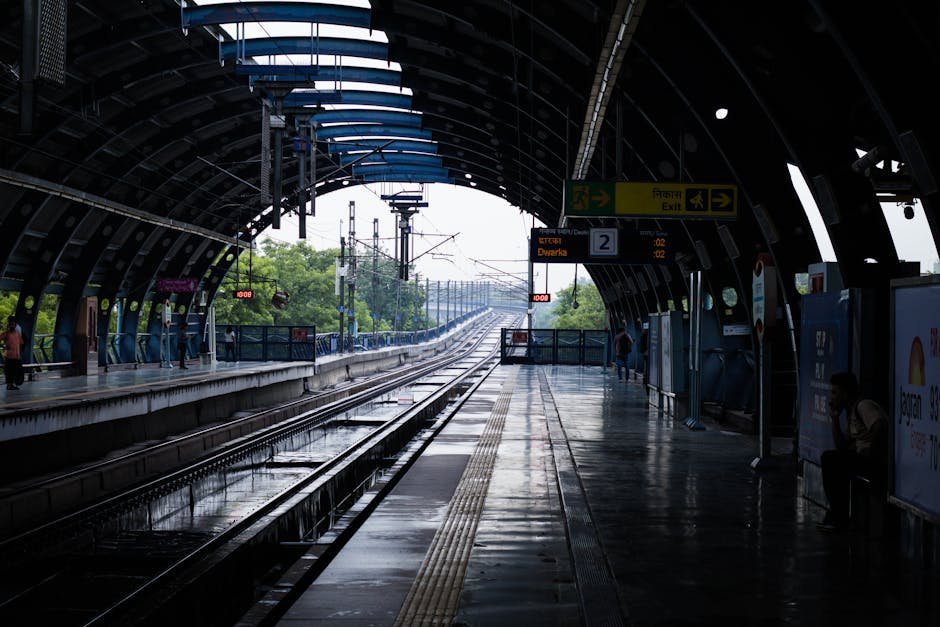 Dwarka Expressway Extension Proposed to Alleviate Delhi-Gurugram Traffic Congestion A quiet afternoon at a New Delhi metro station with wet tracks post rain, reflecting urban life.