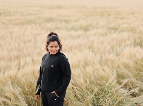 A young woman stands in a golden wheat field enjoying a sunny day. Perfect for rural lifestyle and nature themes.