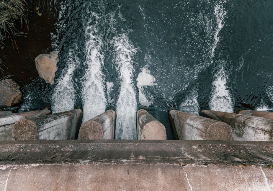 Submerged Temple Emerges in Tamil Nadu as Dam Water Levels Drop Aerial view of cascading water over a concrete dam showcasing turbulent flow and water management.