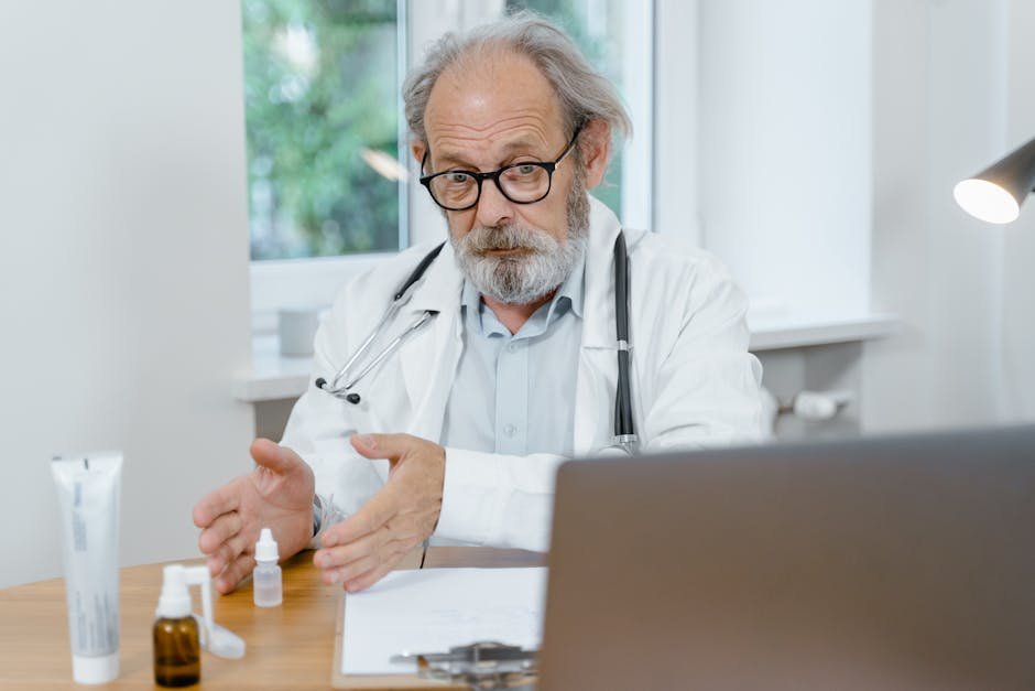 Experts Emphasize Hydration and Awareness to Combat Heat Illnesses in Tamil Nadu An elderly doctor in a white coat conducting an online medical consultation, focusing attentively.