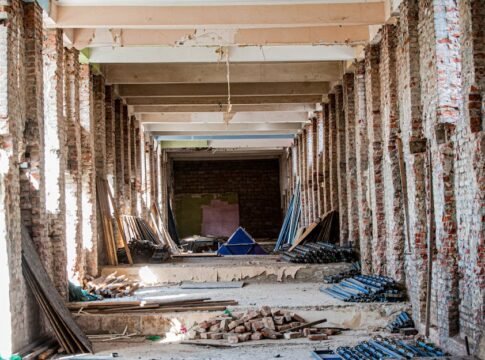 An empty industrial interior undergoing renovation, with exposed brick and construction materials.