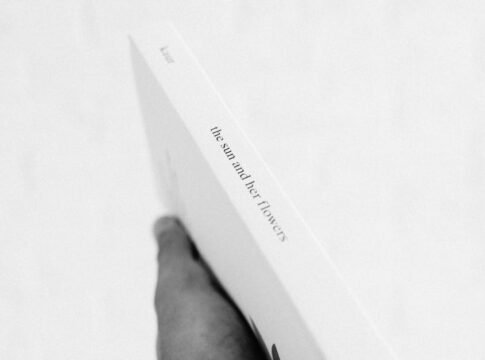 Black and white photo of a hand holding a book, emphasizing simplicity and elegance.