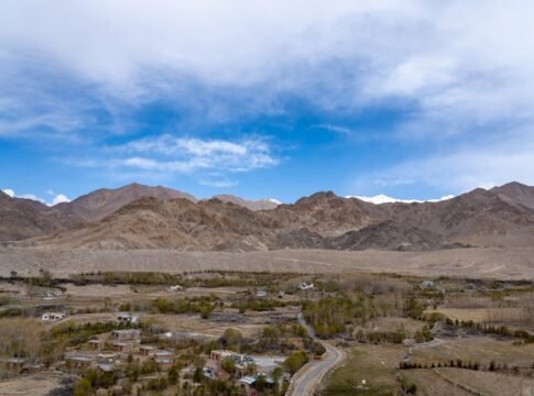 Breathtaking landscape of Leh with majestic mountains and serene valley under a vibrant sky.