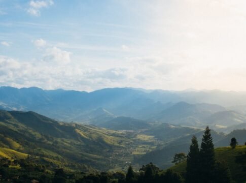 Captivating view of a sunlit valley surrounded by foggy mountains and greenery. Captivating view of a sunlit valley surrounded by foggy mountains and greenery.