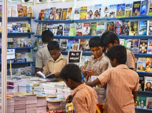 Children engaged in browsing books at a stall in Madurai, highlighting interest in reading and education.