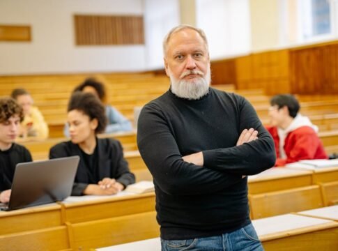 Confident professor in lecture hall with diverse students engaged in learning.