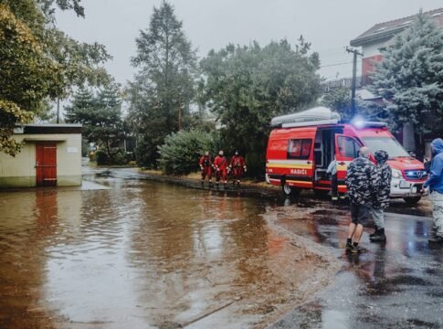 Emergency personnel managing flood with rescue vehicle. Urban scene with standing water.