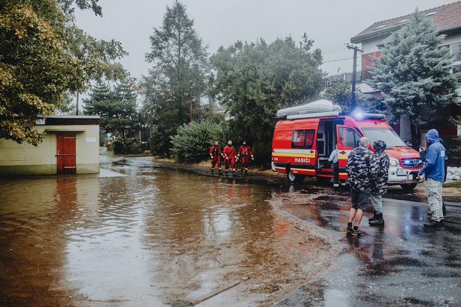 Delhi Launches Five-Day Drive to Rescue Homeless and Destitute Emergency personnel managing flood with rescue vehicle. Urban scene with standing water.