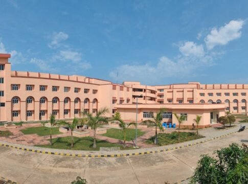 Large educational building with clear blue sky and landscaped grounds.