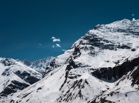 Majestic snow-covered mountains under a clear blue sky in Sissu, Himachal Pradesh, India.