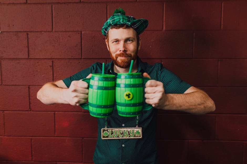 Man celebrating St. Patrick's Day indoors with green mugs and a lucky charm.