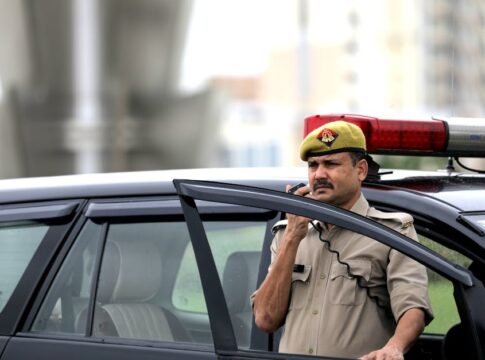 Police officer using radio near patrol car outdoors, ensuring public safety.